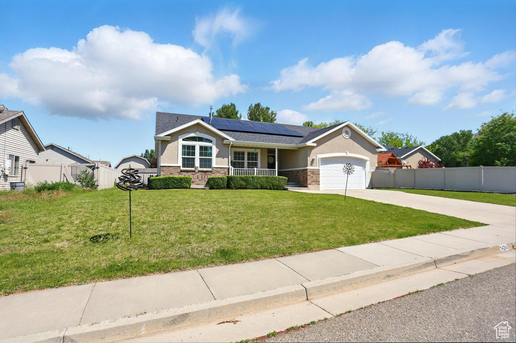 Ranch-style house featuring stucco siding, solar panels, driveway, stone siding, and an attached garage