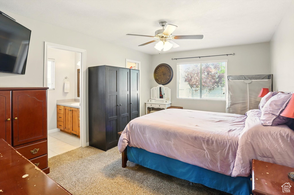 Bedroom featuring ensuite bathroom, a ceiling fan, and light tile patterned floors