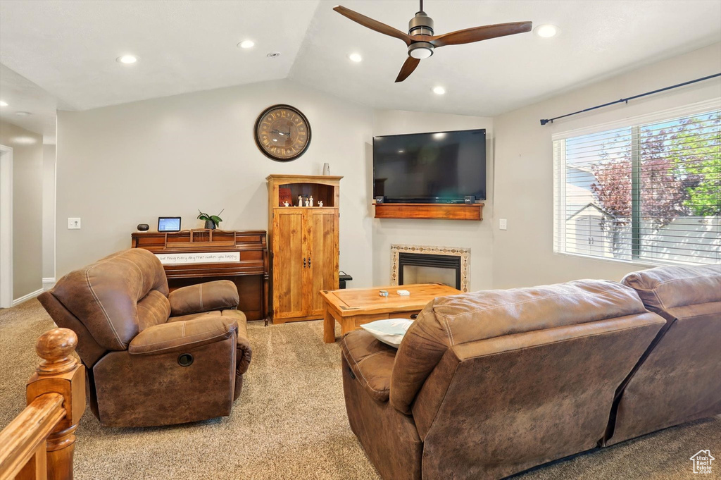 Living room featuring light carpet, a ceiling fan, a fireplace, vaulted ceiling, and recessed lighting