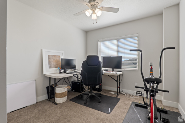 Carpeted office with a ceiling fan and baseboards