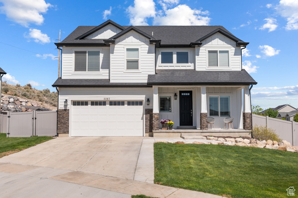Craftsman-style home featuring covered porch, a gate, board and batten siding, and an attached garage