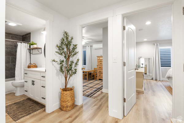 Bathroom with a wall mounted air conditioner, wood finished floors, connected bathroom, vanity, and ceiling fan