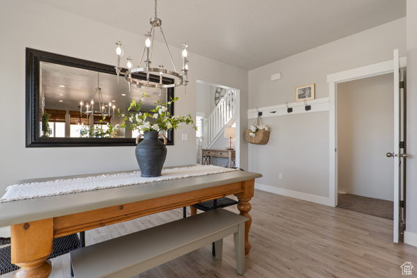 Dining space featuring a chandelier, wood finished floors, stairway, and baseboards