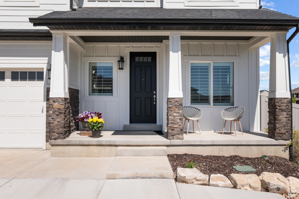 Property entrance with covered porch, board and batten siding, stone siding, and roof with shingles