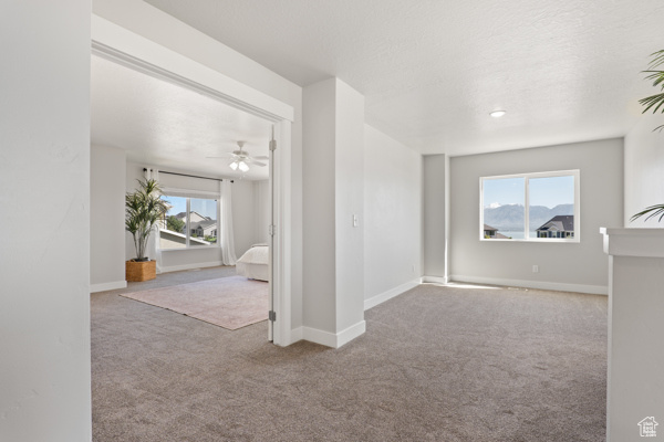 Carpeted empty room featuring a ceiling fan and baseboards
