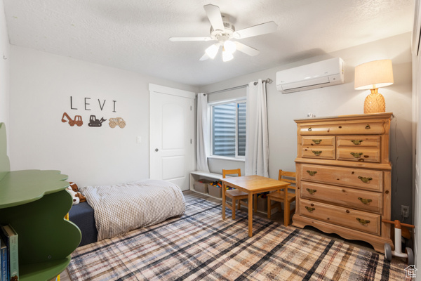 Bedroom with a wall unit AC and a ceiling fan