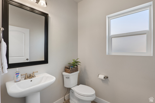 Half bath with baseboards, a sink, and toilet