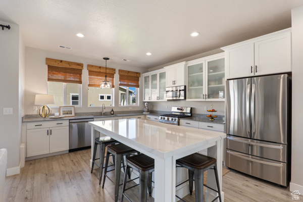 Kitchen featuring stainless steel appliances, a sink, light wood finished floors, white cabinets, and recessed lighting