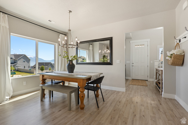 Dining room with a chandelier, light wood-type flooring, and baseboards