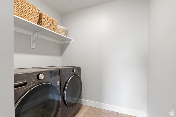 Washroom with separate washer and dryer, baseboards, and light tile patterned floors