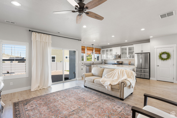Living room with ceiling fan, light wood-style floors, recessed lighting, and baseboards