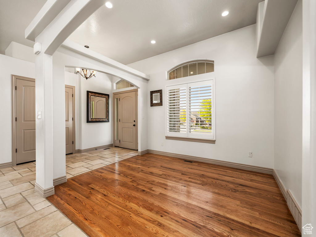 Empty room with a chandelier, recessed lighting, wood finished floors, baseboards, and arched walkways