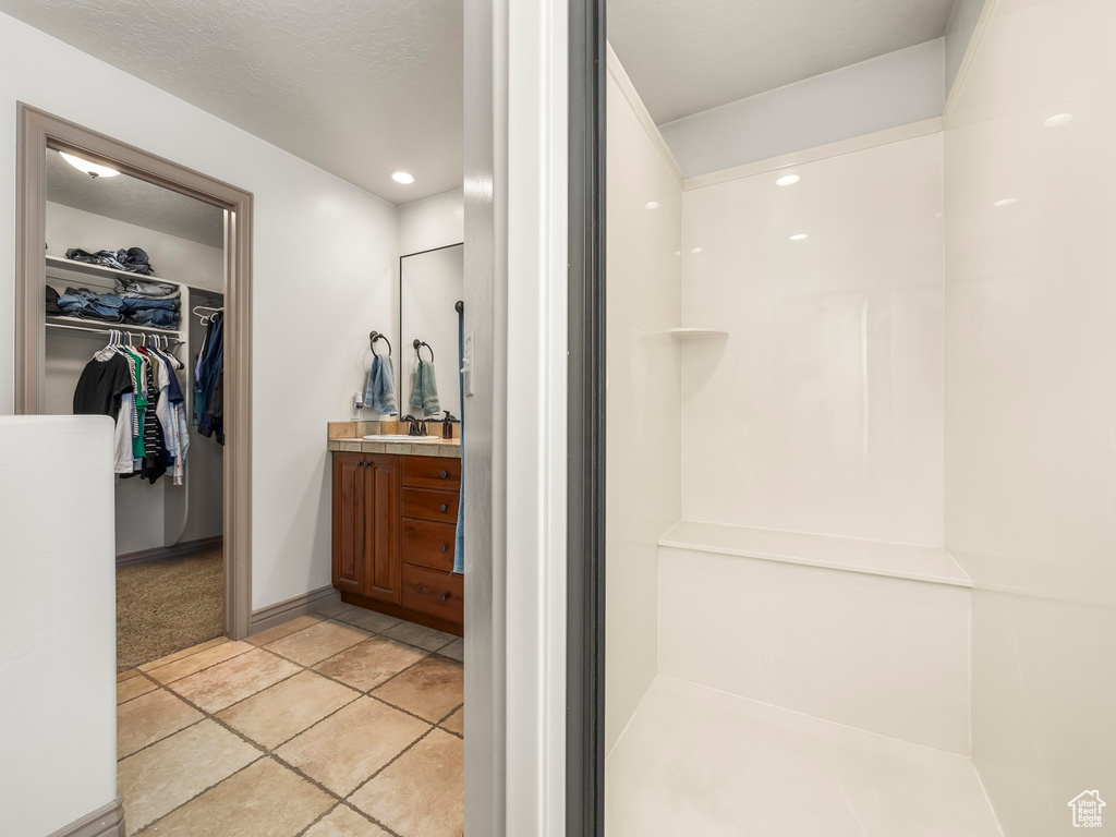 Full bath with vanity, a spacious closet, a shower, and recessed lighting
