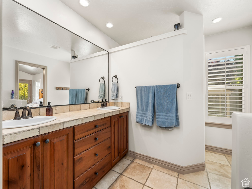 Ensuite bathroom with double vanity, recessed lighting, and baseboards