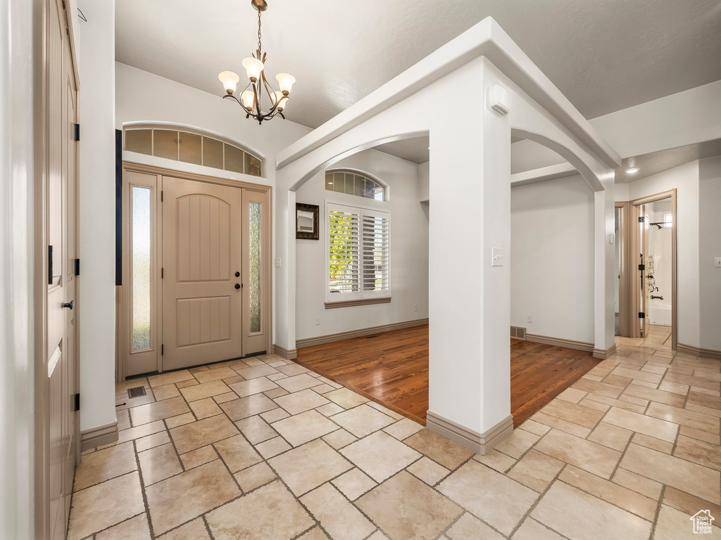 Foyer entrance featuring arched walkways, stone tile flooring, a chandelier, and baseboards