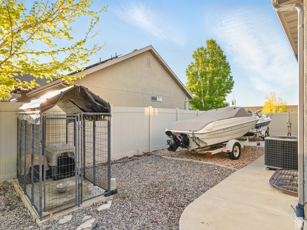 View of side of home with fence, an exterior structure, cooling unit, and an outbuilding