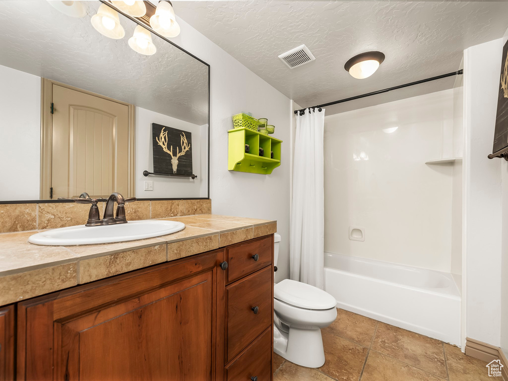 Full bath featuring shower / tub combo, toilet, vanity, and a textured ceiling
