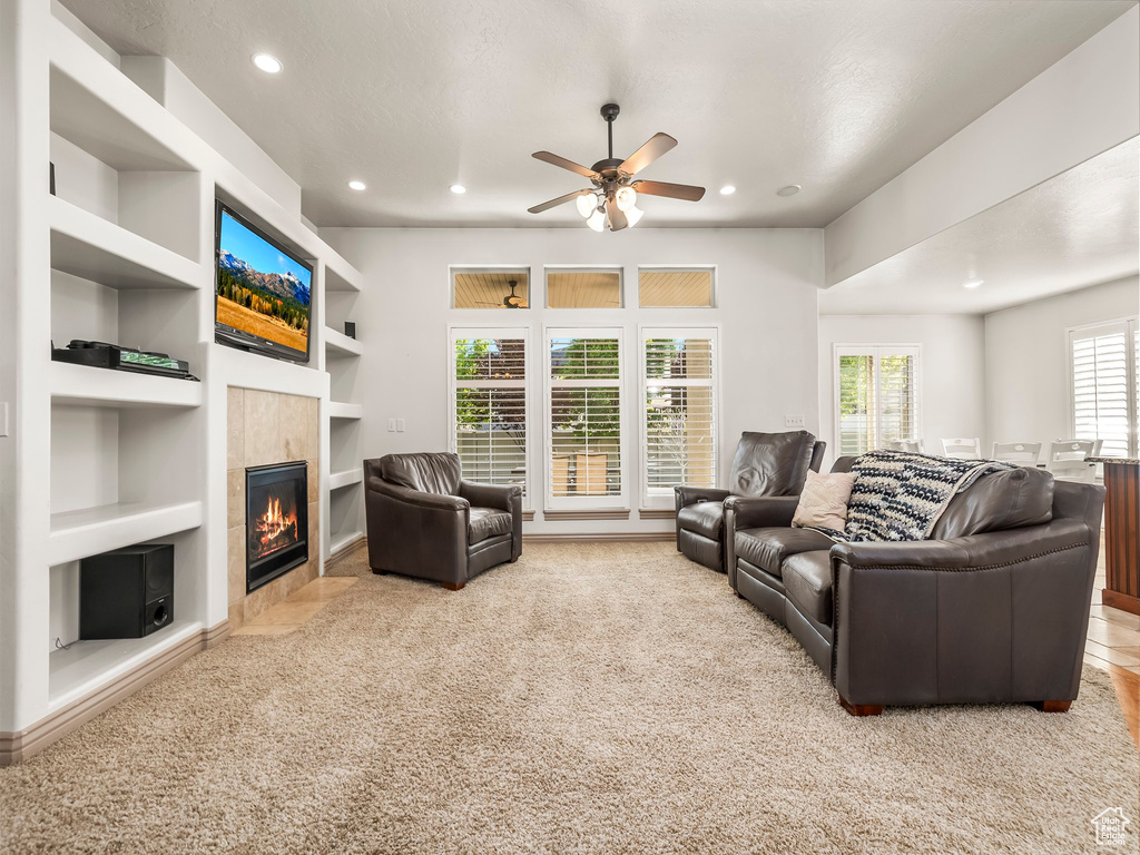 Carpeted living area with built in shelves, a tiled fireplace, recessed lighting, and ceiling fan