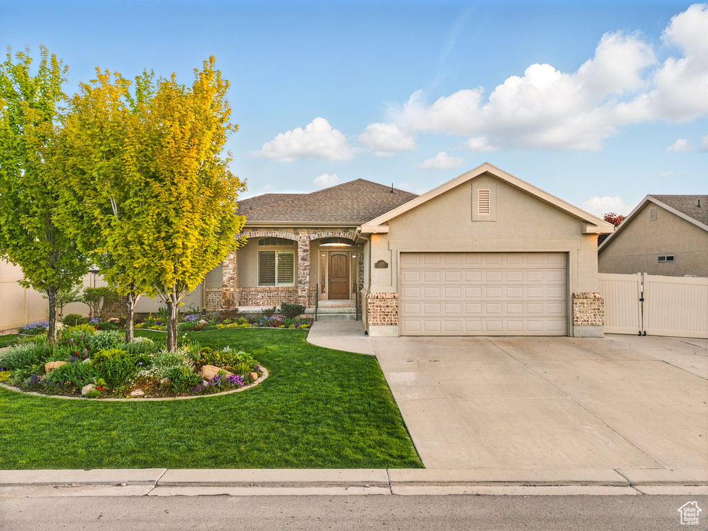 View of front facade featuring a garage, concrete driveway, stucco siding, and a gate