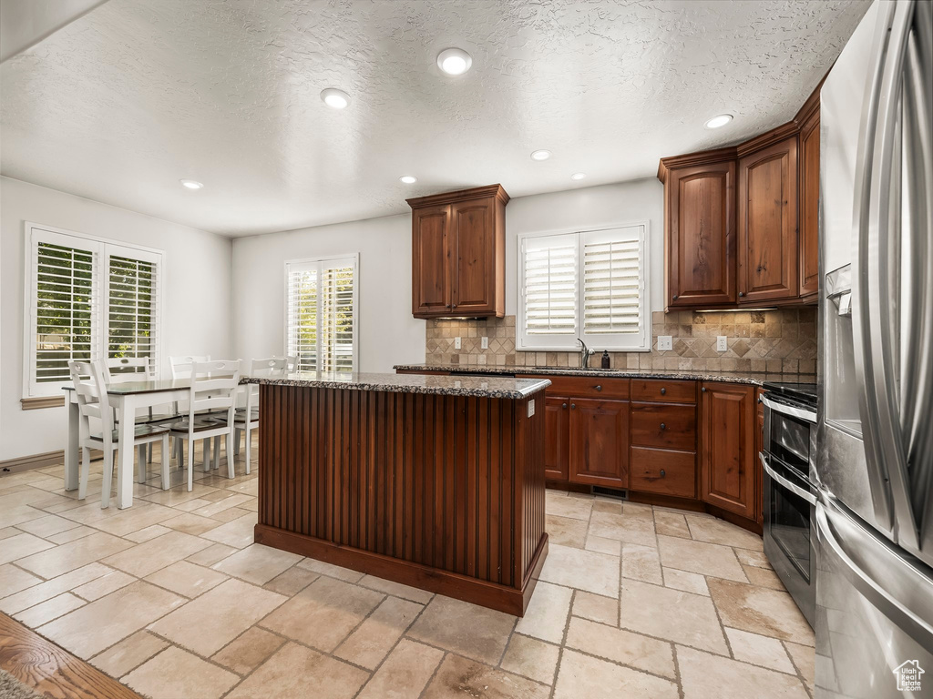 Kitchen featuring stainless steel appliances, decorative backsplash, a sink, a kitchen island, and recessed lighting