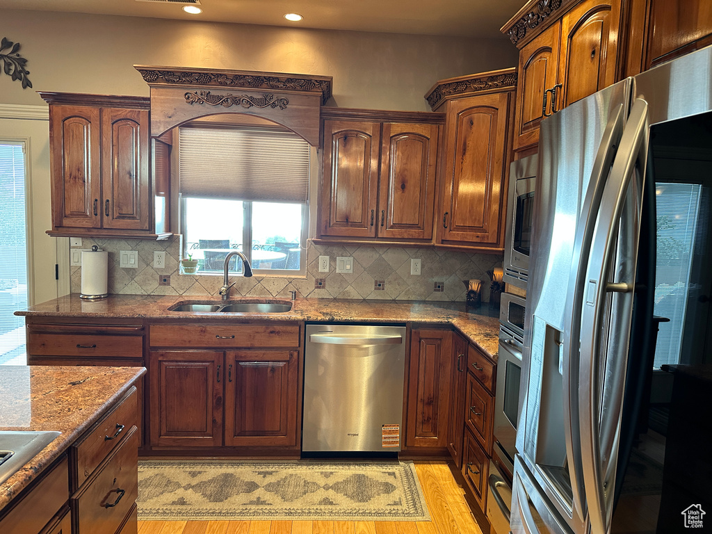 Kitchen with stainless steel appliances, a sink, stone counters, backsplash, and recessed lighting