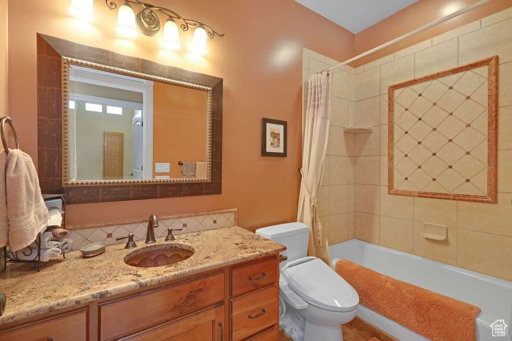 Bathroom with toilet, vanity, shower / tub combo with curtain, and backsplash