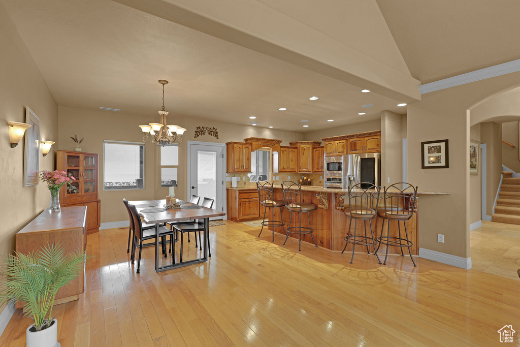 Kitchen featuring stainless steel appliances, arched walkways, a breakfast bar area, brown cabinets, and recessed lighting
