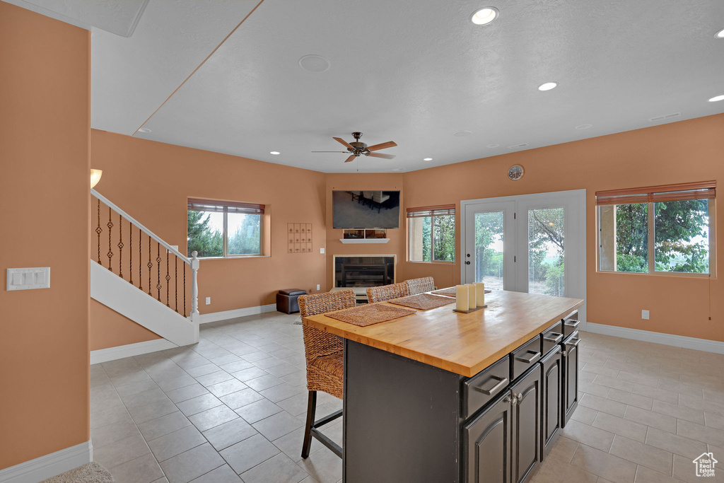 Kitchen with butcher block countertops, plenty of natural light, a tiled fireplace, baseboards, and recessed lighting