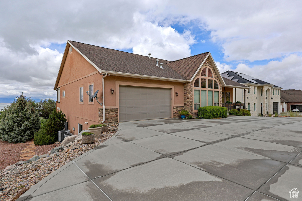 View of front facade with stucco siding, stone siding, concrete driveway, an attached garage, and a shingled roof