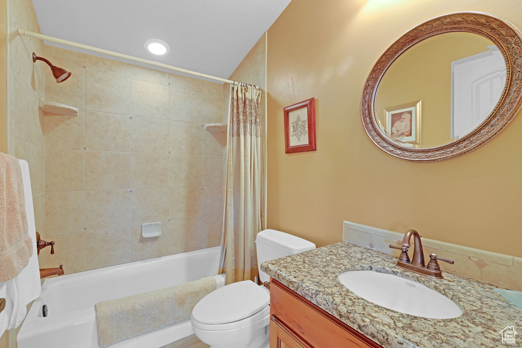 Bathroom featuring toilet, shower / bath combo with shower curtain, and vanity