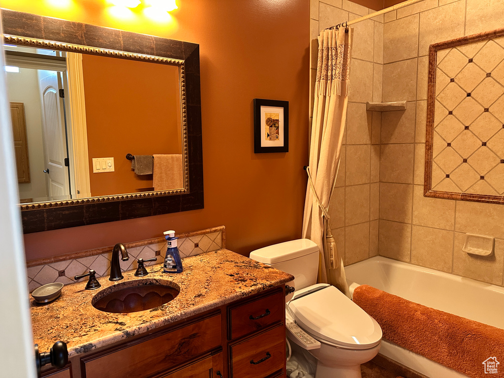 Bathroom with vanity, toilet, and shower / bath combination with curtain
