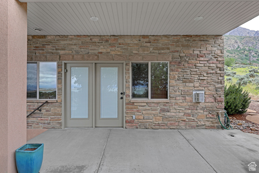 View of exterior entry featuring stone siding, a patio, and a mountain view