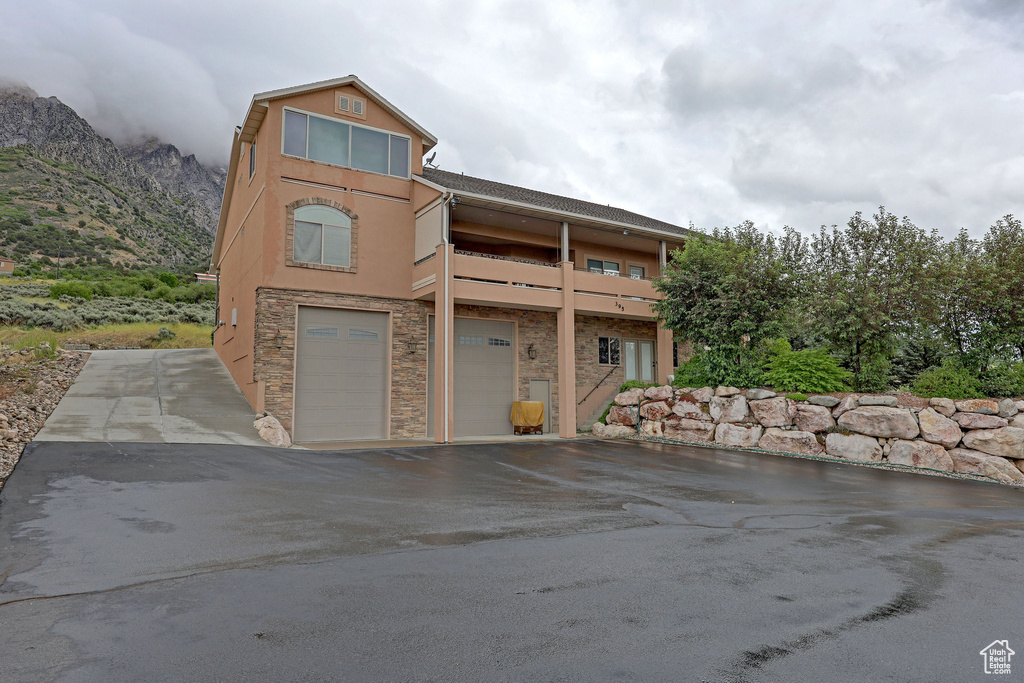 View of front facade with a garage, stucco siding, stone siding, driveway, and a mountain view