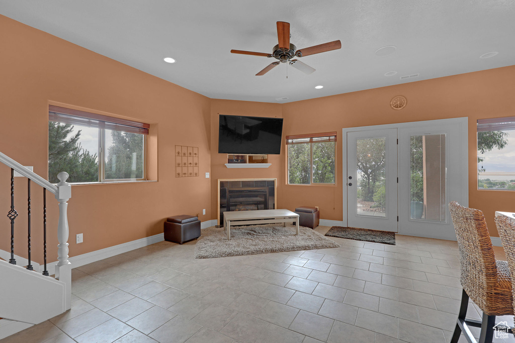 Unfurnished living room featuring healthy amount of natural light, a tile fireplace, a ceiling fan, recessed lighting, and baseboards