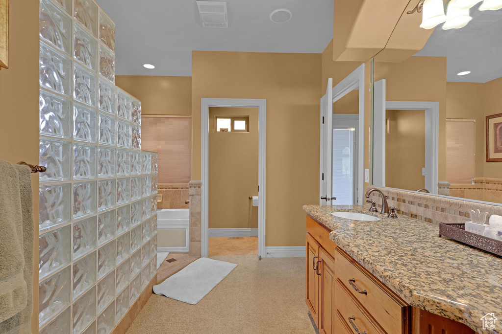 Bathroom featuring baseboards, vanity, and a garden tub