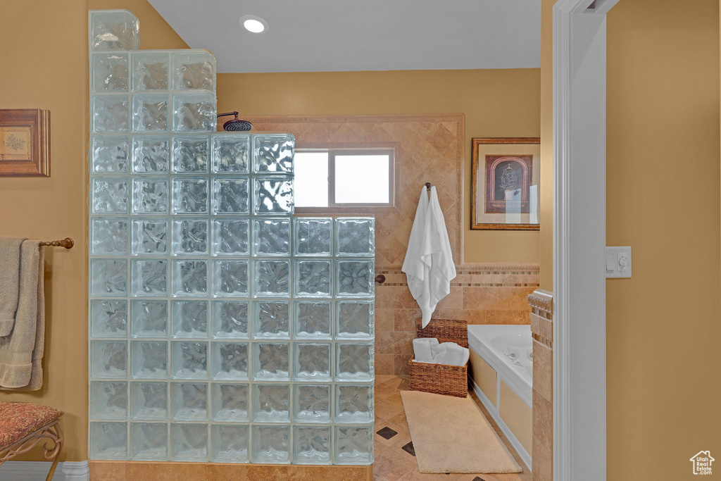 Full bathroom featuring walk in shower, a bath, and tile walls