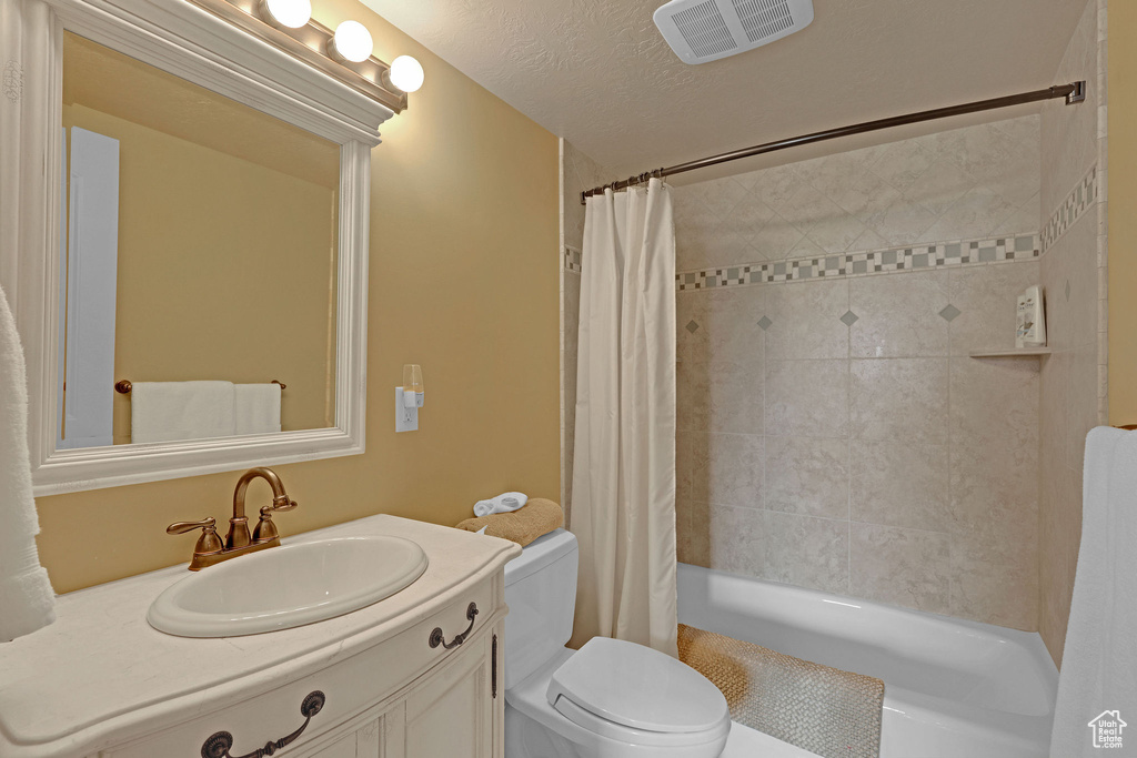 Full bathroom featuring toilet, vanity, and shower / bath combination with curtain