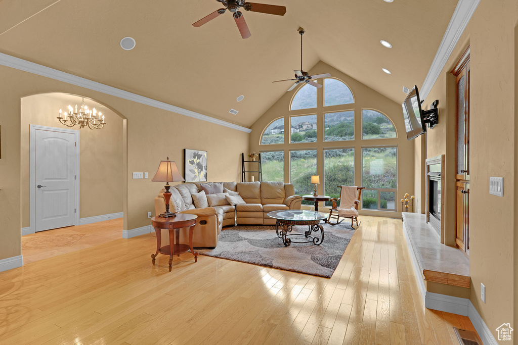Living room with a ceiling fan, light wood-type flooring, high vaulted ceiling, a high end fireplace, and baseboards