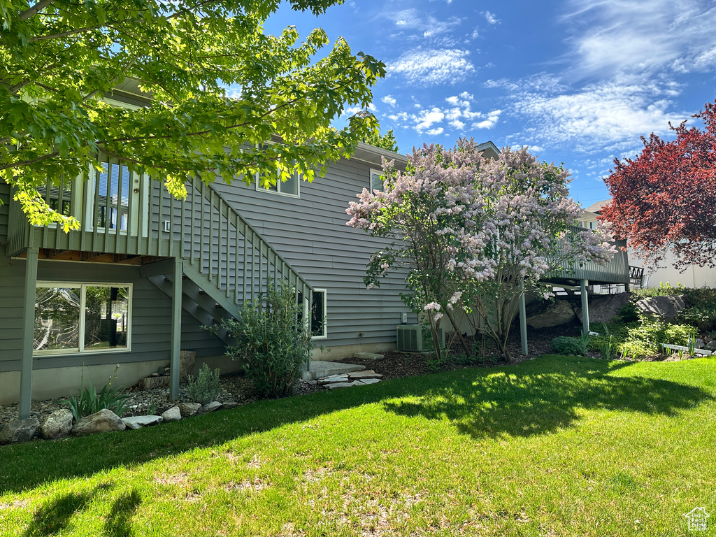 View of property exterior with stairway, a lawn, and central AC