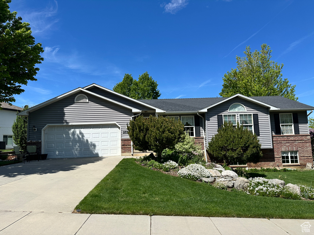 Ranch-style home featuring brick siding, an attached garage, driveway, and a front yard