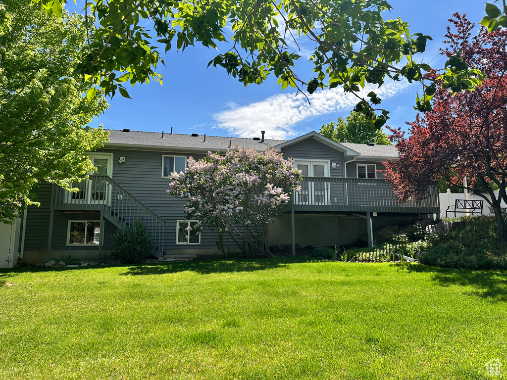 Back of house featuring a yard, a wooden deck, and stairway
