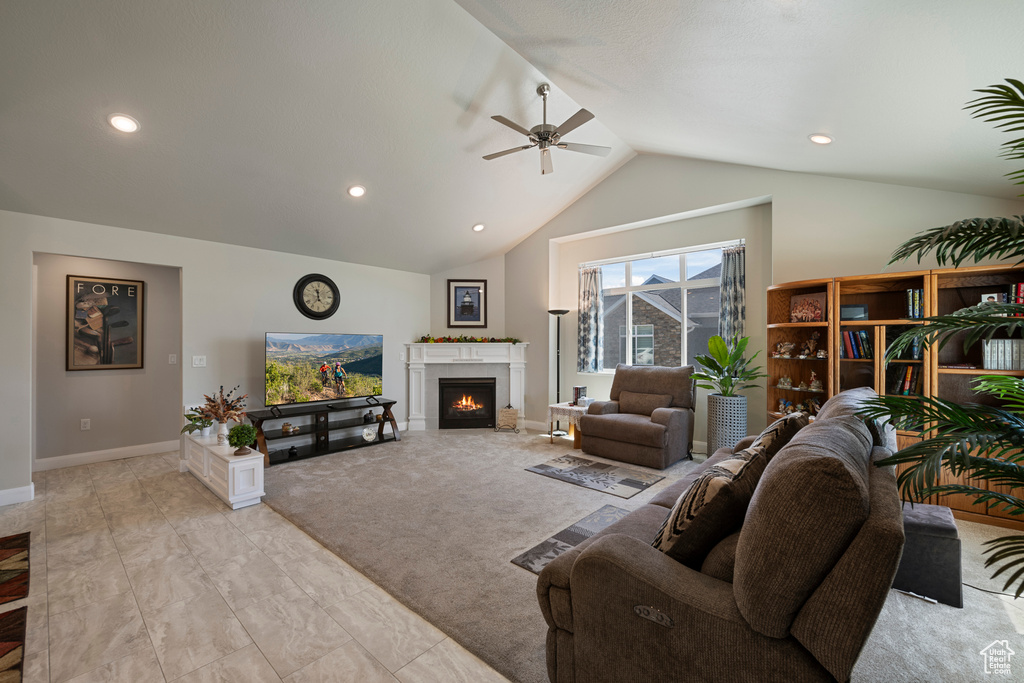Living room with vaulted ceiling, ceiling fan, a warm lit fireplace, baseboards, and recessed lighting