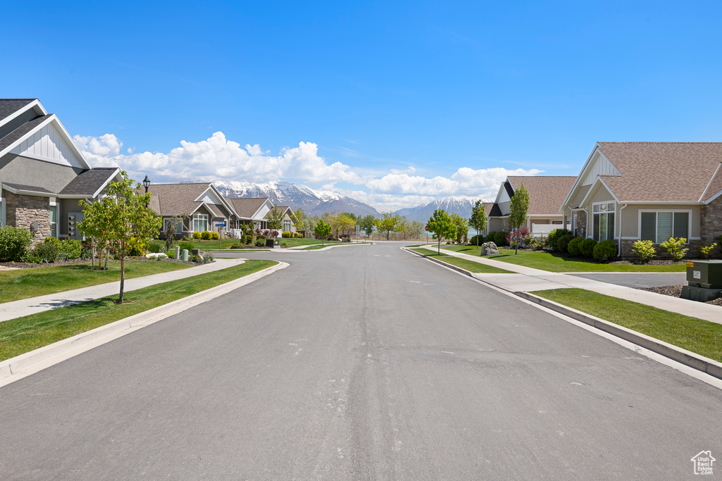View of asphalt road with a residential view, sidewalks, a mountain view, and curbs
