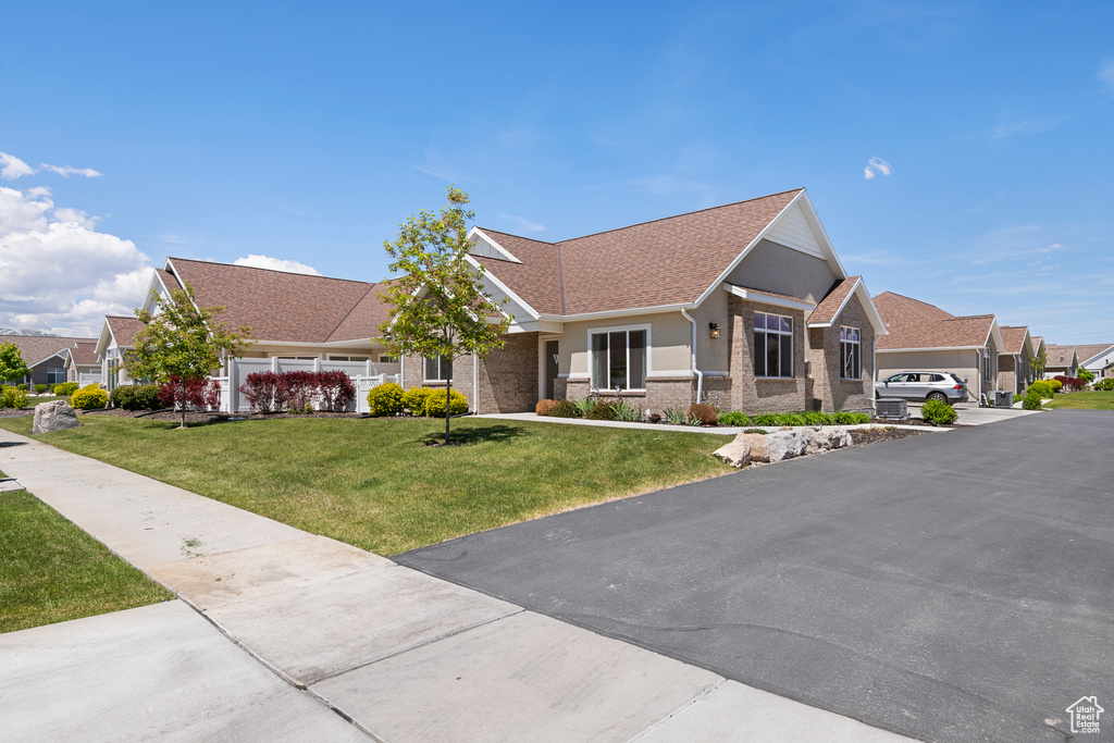 View of front of house featuring a front yard, a residential view, a shingled roof, and stucco siding