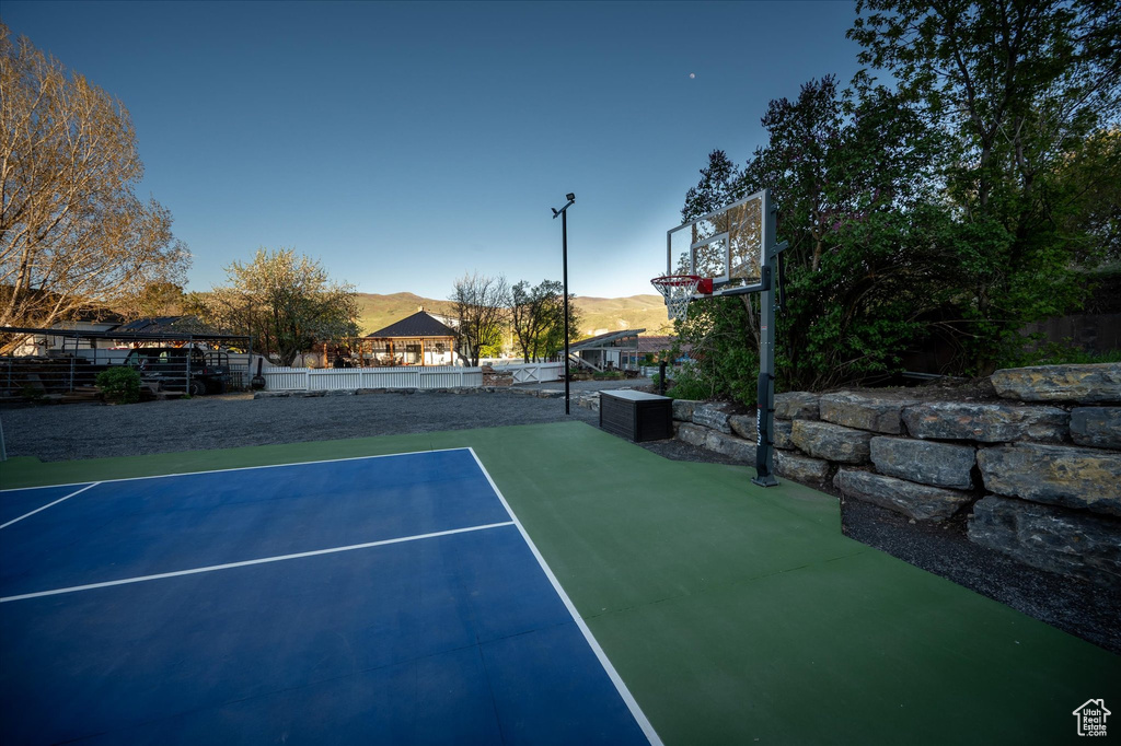 View of sport court with a mountain view, basketball court, a tennis court, and fence