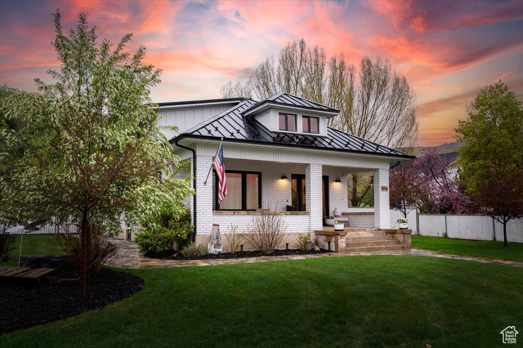 View of front of house featuring a standing seam roof, brick siding, covered porch, and metal roof