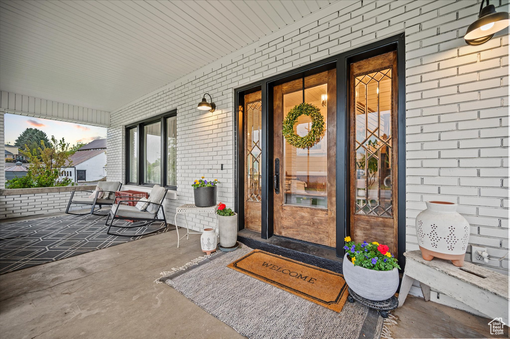 Doorway to property with a porch and brick siding