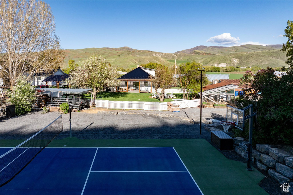 View of basketball court featuring a mountain view, fence, and a tennis court