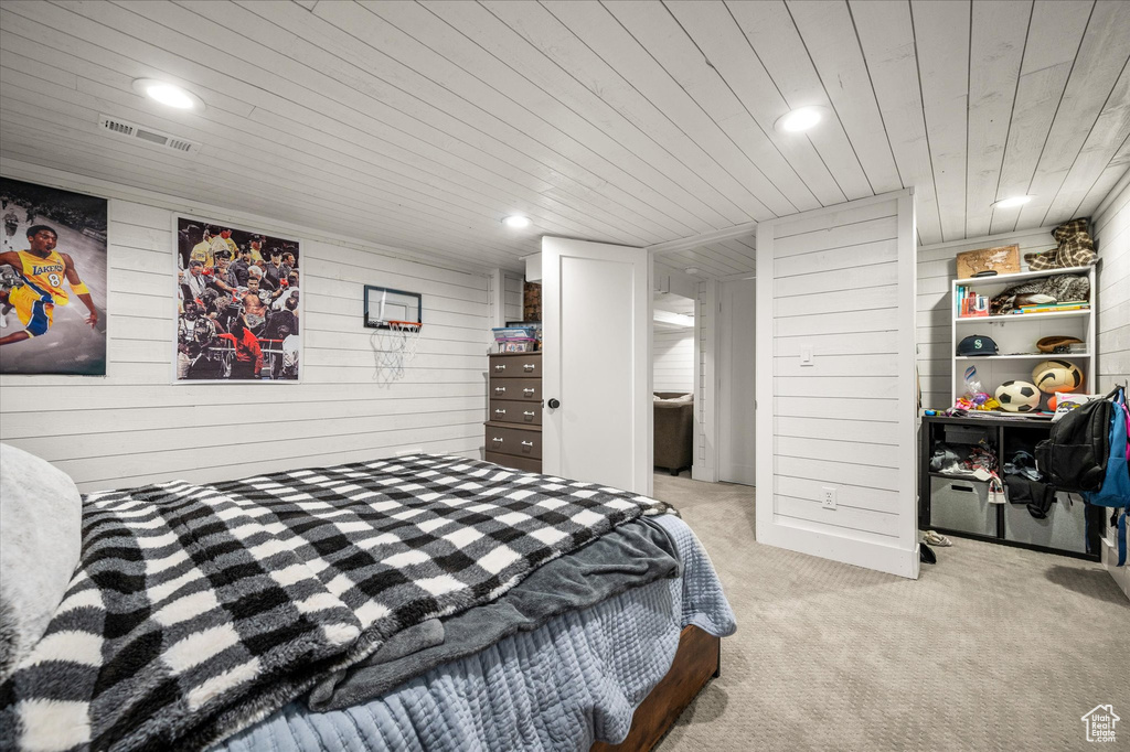 Bedroom with light colored carpet, wood ceiling, wood walls, and recessed lighting