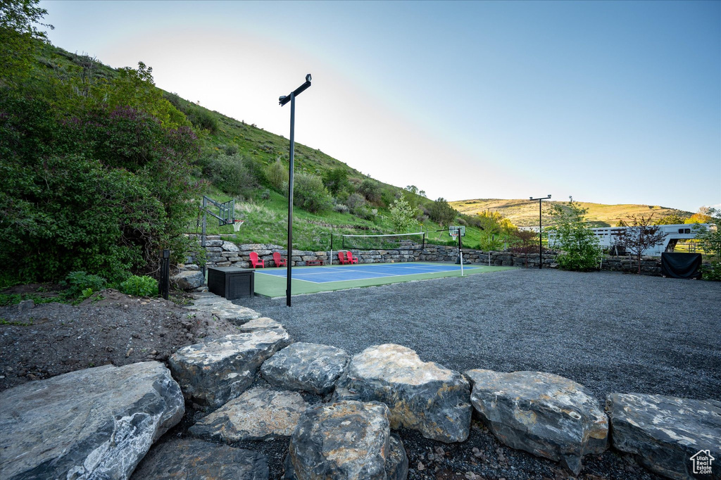 View of property\'s community with a tennis court, fence, and a mountain view